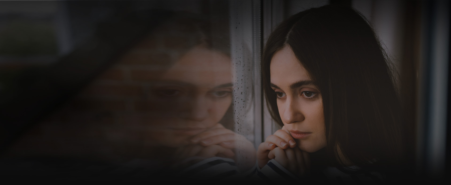 sad woman looks out window