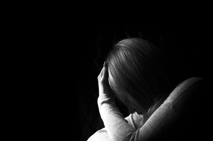 Woman with hand on head looking down