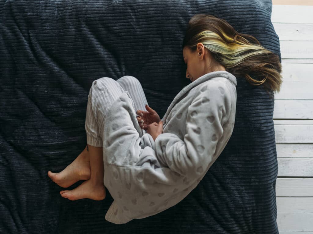 Woman curled up on top of bed