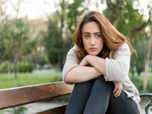 A worried woman sitting on a park bench