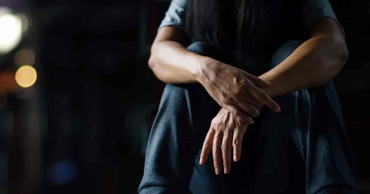 Person sitting on ground with hands crossed