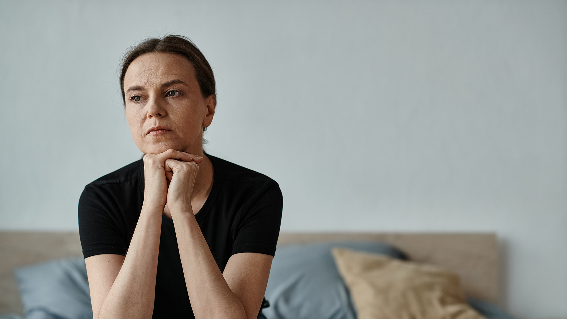 woman sitting on bed, deep in thought
